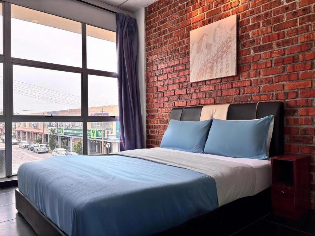 a bedroom with a brick wall and a bed with blue pillows at Above A Shoplot No Noise Worries 12Pax & FreeWiFi in Ipoh