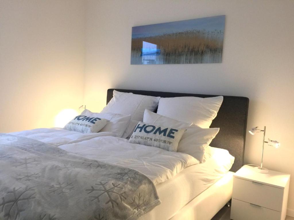 ein weißes Bett mit Kissen darauf im Schlafzimmer in der Unterkunft Apartment Warnemünde 15 in Warnemünde