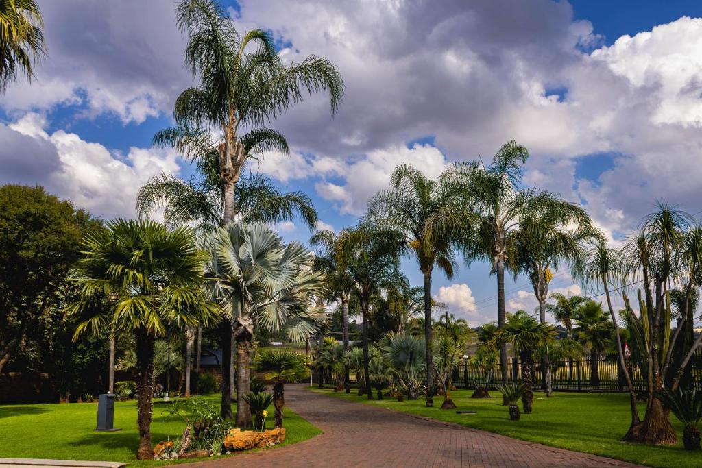 a park with palm trees and a path at Palmera Guest House in Krugersdorp