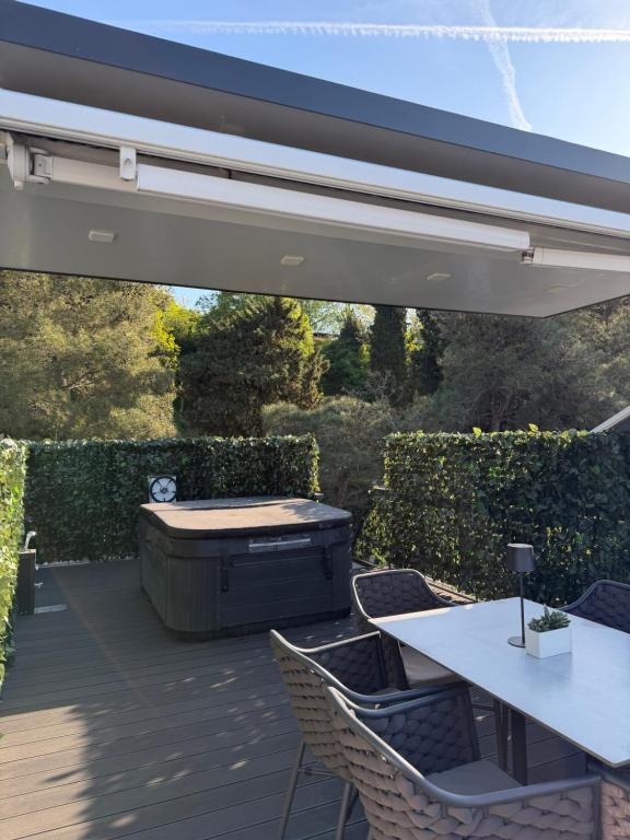 a patio with a hot tub and a table and chairs at JungleHouse - Floating House in Portorož