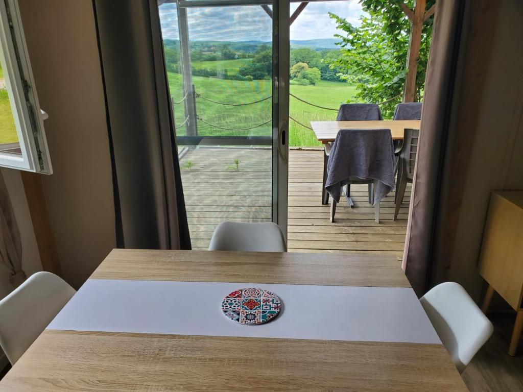 a table in a room with a view of a deck at Les chalets du Causse Confort Climatisé in Gelle