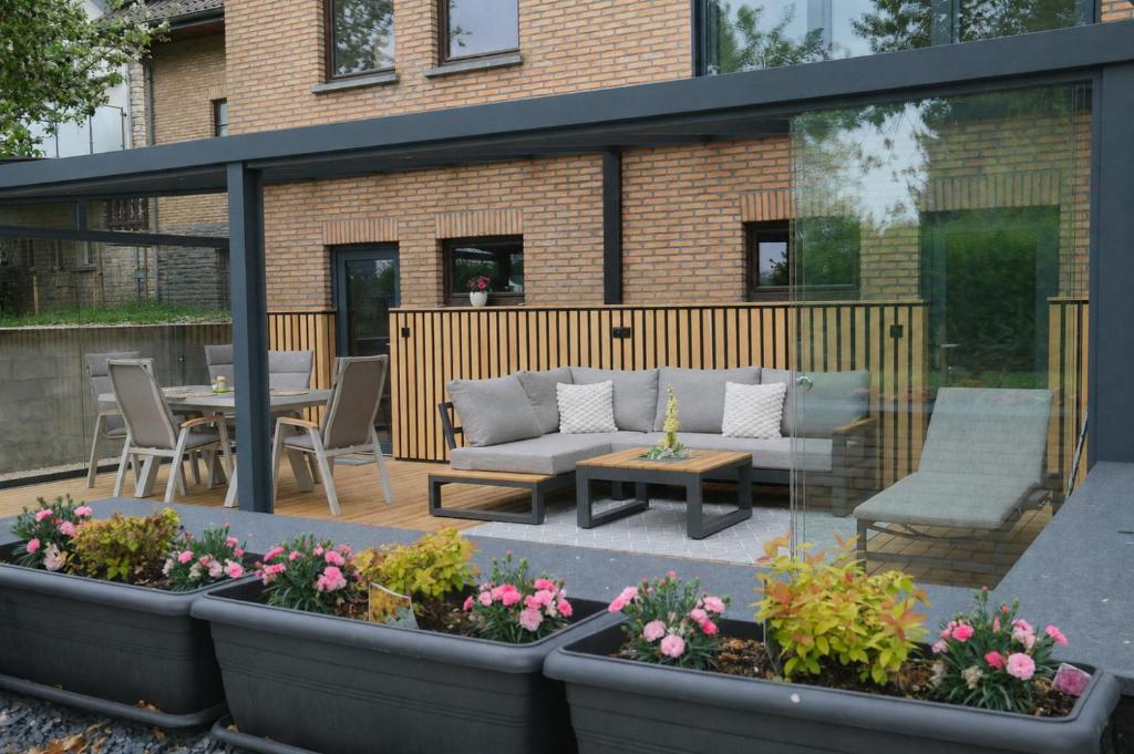 a patio with a couch and a table and some flowers at Eifeltraum Marianus in Nieder-Emmels