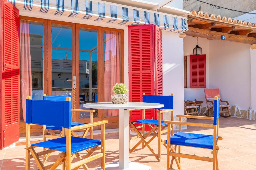 a table and chairs on a patio with red and blue chairs at Can Pons in Can Picafort