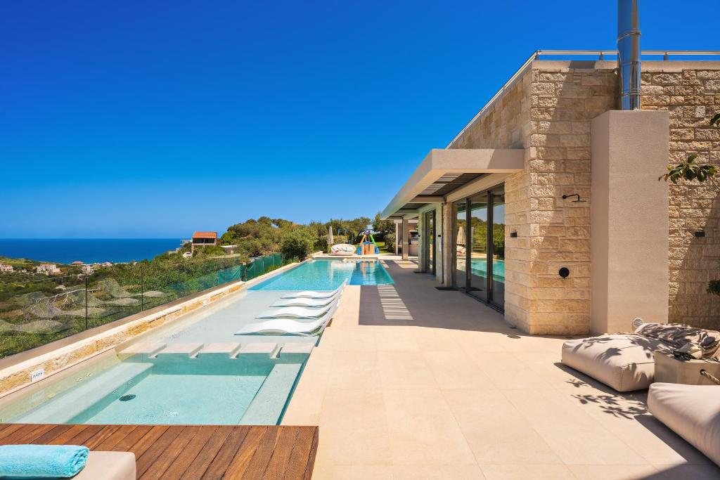 a swimming pool with lounge chairs and the ocean at Villa Reale - Wellness & Refined Living by etouri in Chania