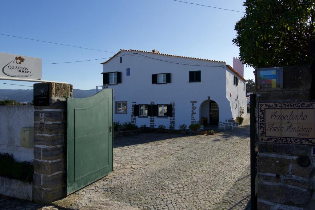a white house with a green gate in front of it at Casalinho De Santo António in Sintra