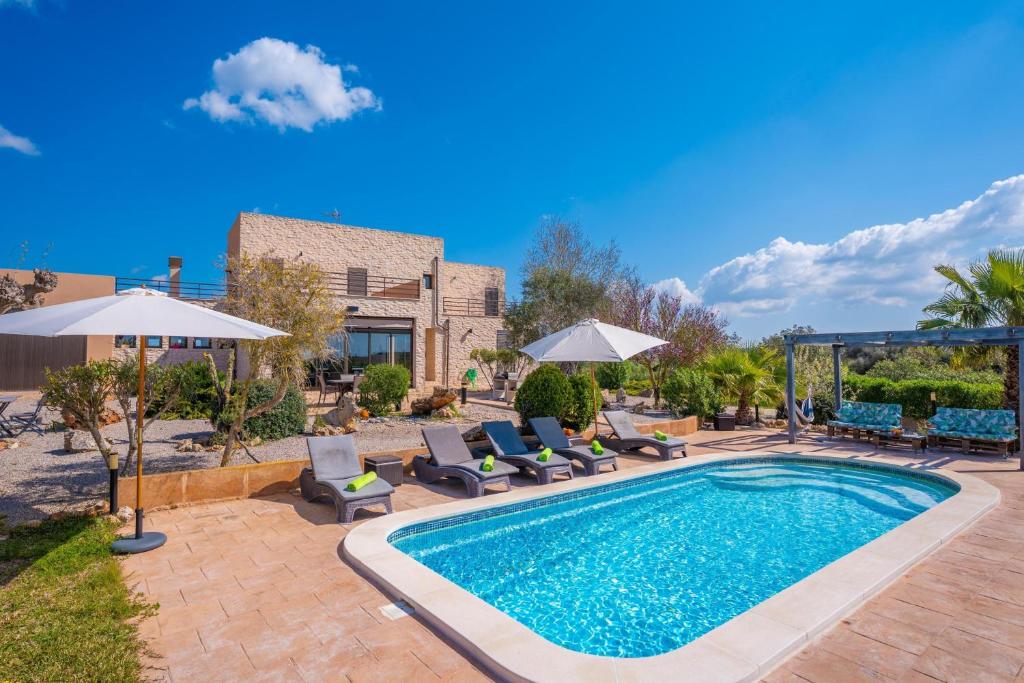 a pool with chairs and umbrellas next to a building at Son Vigili in Campos