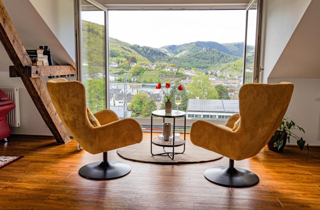 a room with two chairs and a table and a large window at Ferienwohnungen Moselpanorama und Moselblick in Bullay