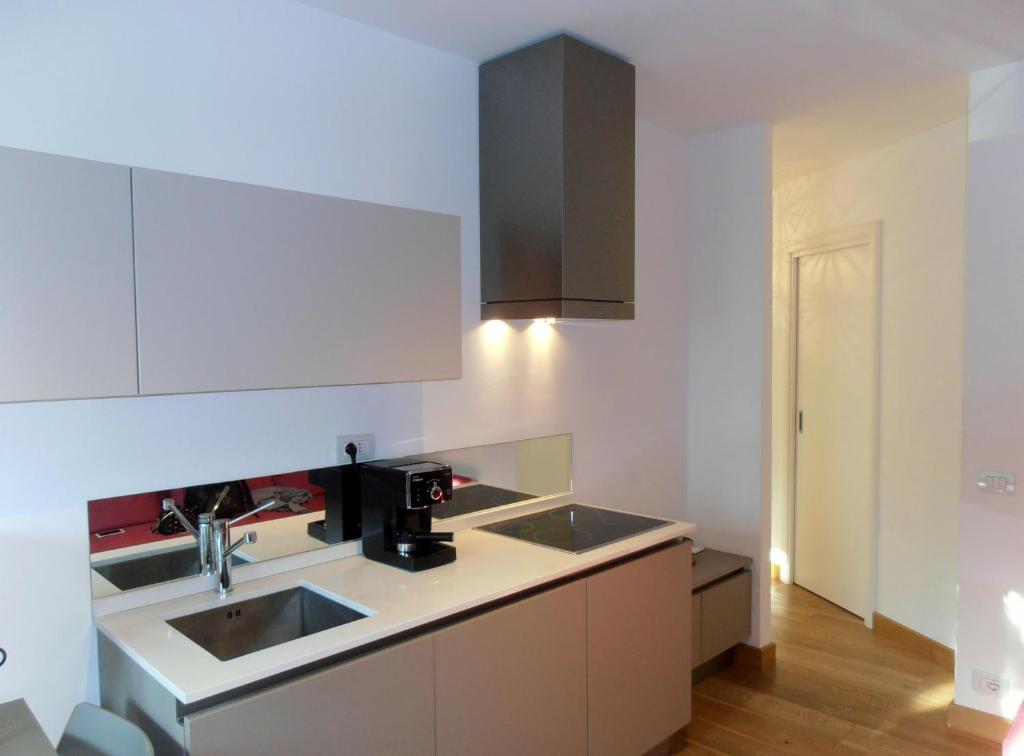 una cocina con armarios blancos y fregadero en Appartamento Monti e Relax, en Saint Vincent