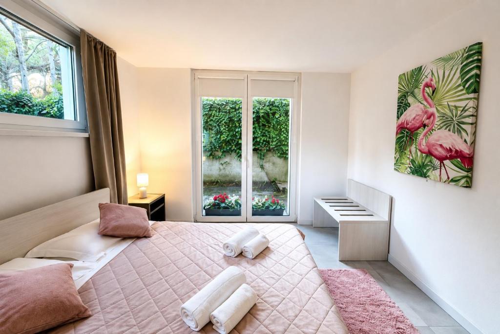a bedroom with a pink bed and a window at Villa Greif Pineta Apartment in Lignano Sabbiadoro