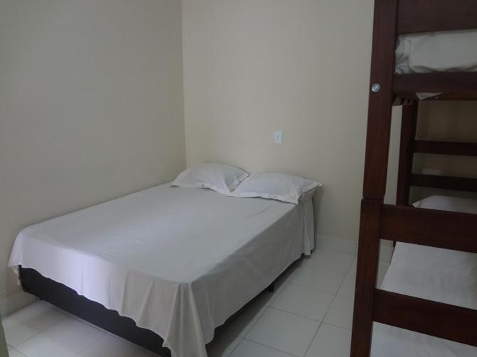 a white bed in a room with a ladder at Pousada PG One in Praia Grande