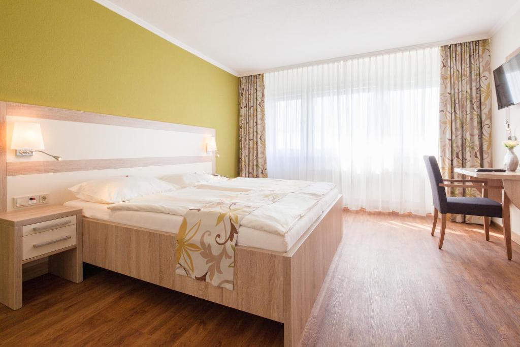 a bedroom with a bed and a desk and a window at GDA Hotel Göttingen in Göttingen