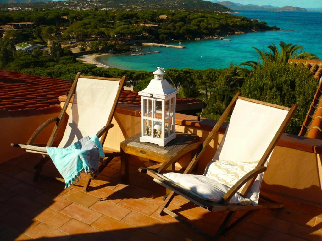 two chairs and a lantern on a balcony with the ocean at La Casa delle Conchiglie in Capo Coda Cavallo