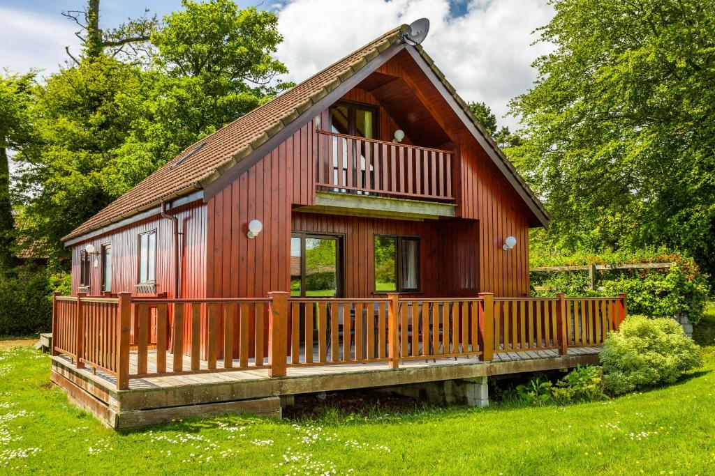a red house with a deck on the grass at E29 -Lawnside in Truro