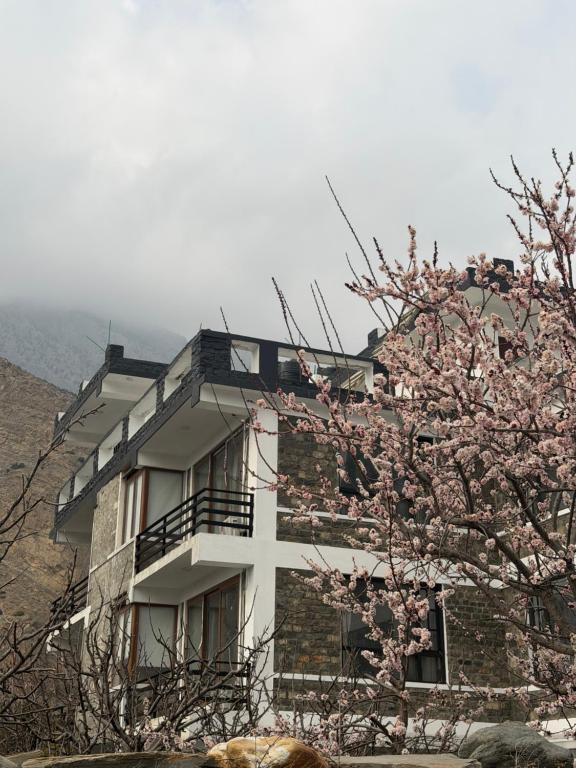 a building with a cross in front of a flowering tree at Bön Valley in Jomsom