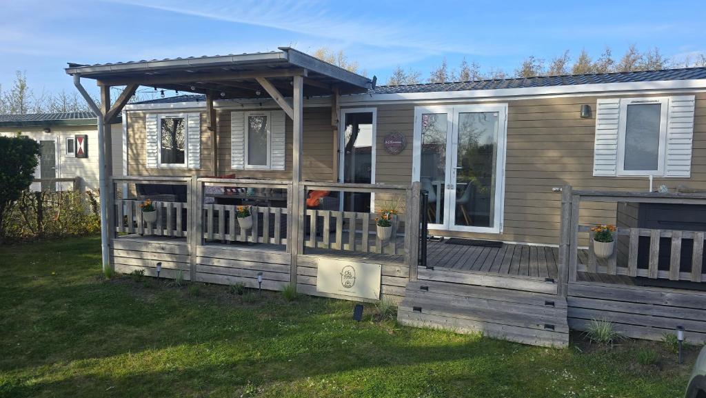 a wooden house with a porch and a fence at Het Strandnest in Renesse