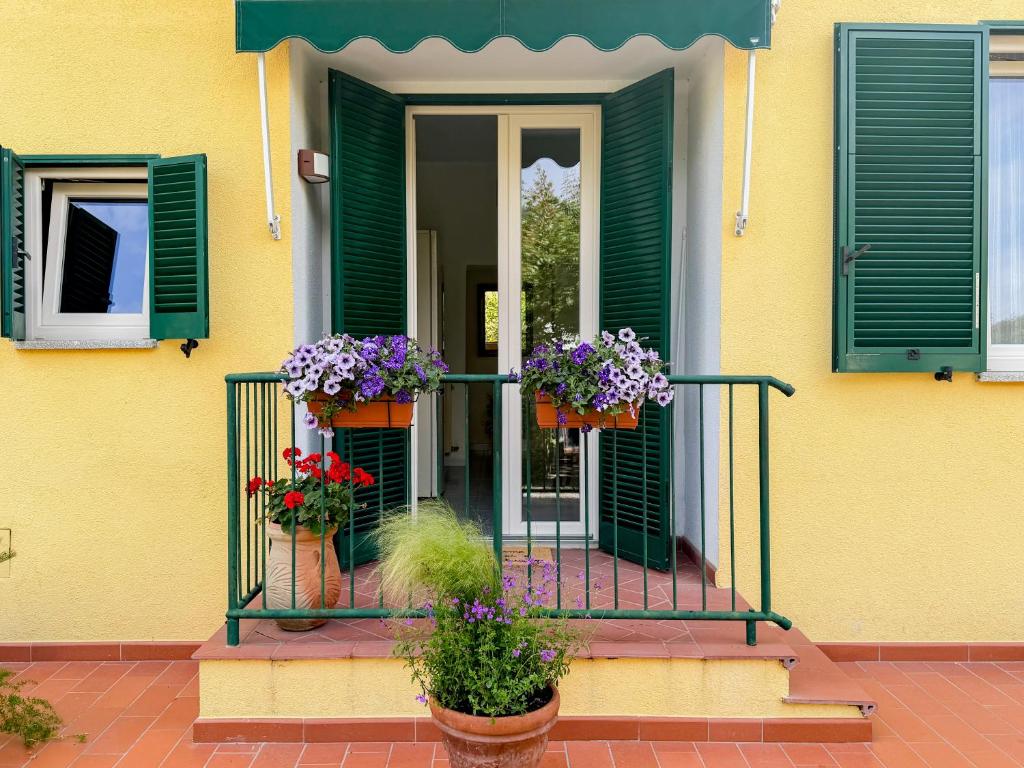 a yellow house with green shutters and flowers on a balcony at Casa di Leo - HelloElba in Portoferraio