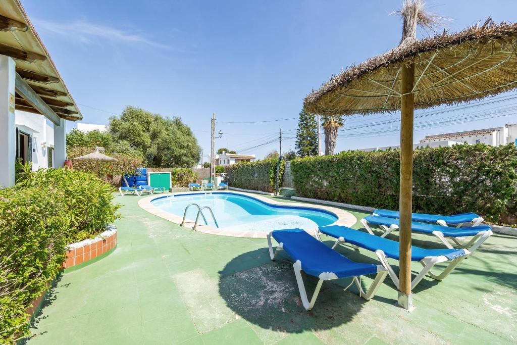 a swimming pool with blue chairs and an umbrella at Apartamento Felipe 2-2 in Cala d´Or