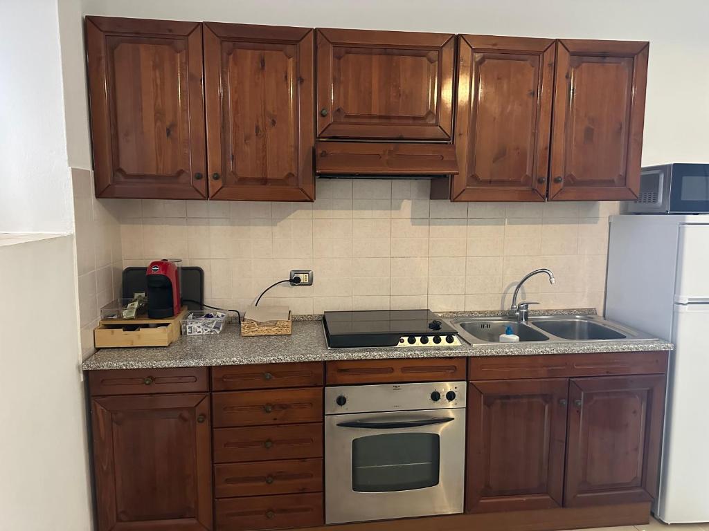 a kitchen with wooden cabinets and a stove and a sink at Casa vacanze Pezzoli in Rovato