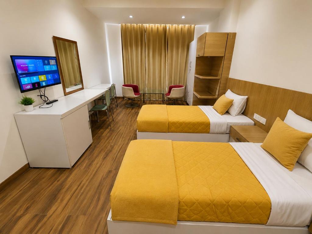 a hotel room with two beds and a television at FlexiBay Boys Hostel Noida in Noida