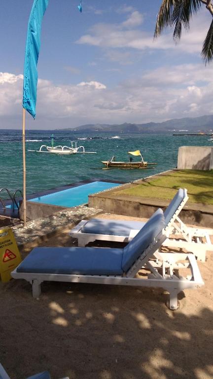 Aquaria Eco Resort في كانديداسا: زوج من كراسي الصالة على الشاطئ بالقرب من الماء