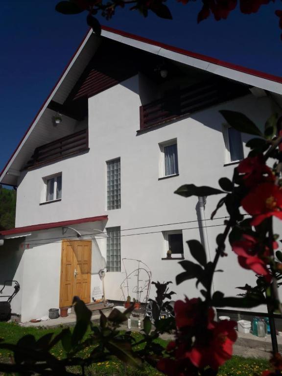 a white building with a brown door and some flowers at Casa Ionela nr 13- Complex de pensiuni si Casute la Munte in Ceahlău