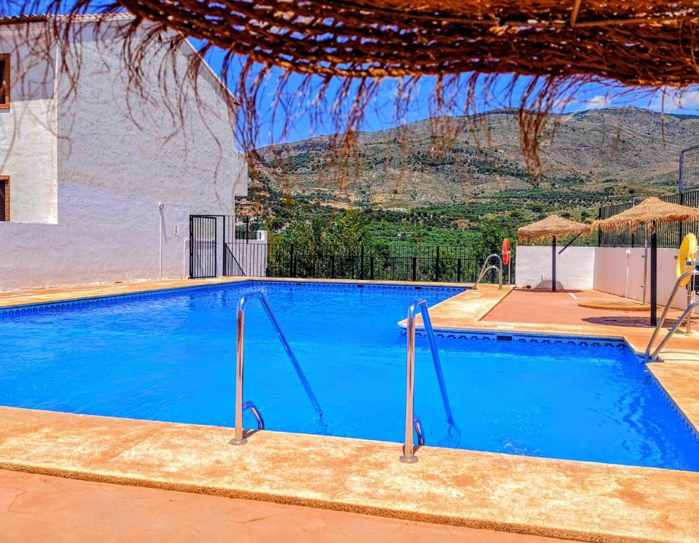 a large blue swimming pool with a mountain in the background at Casona El Chaparral in Fondón