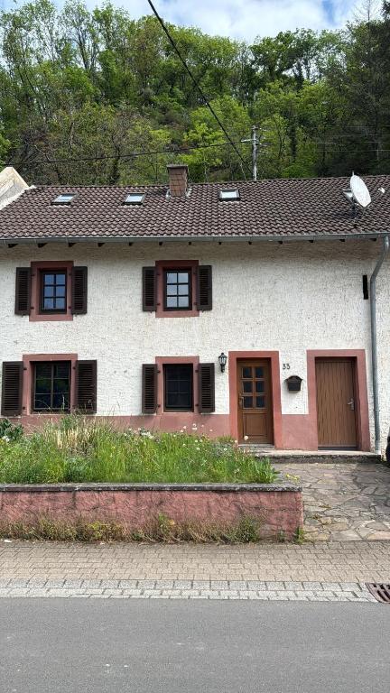 a white house with brown shuttered windows at Haus in Roth an der Our in Roth