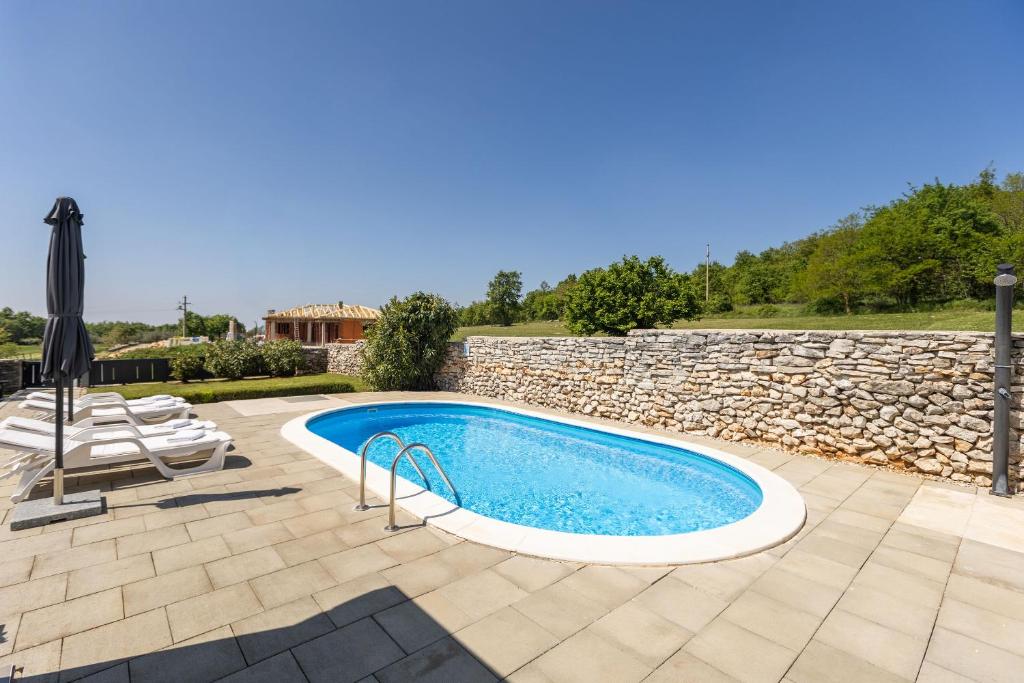 a swimming pool with an umbrella and a stone wall at House Prenc in Pazin