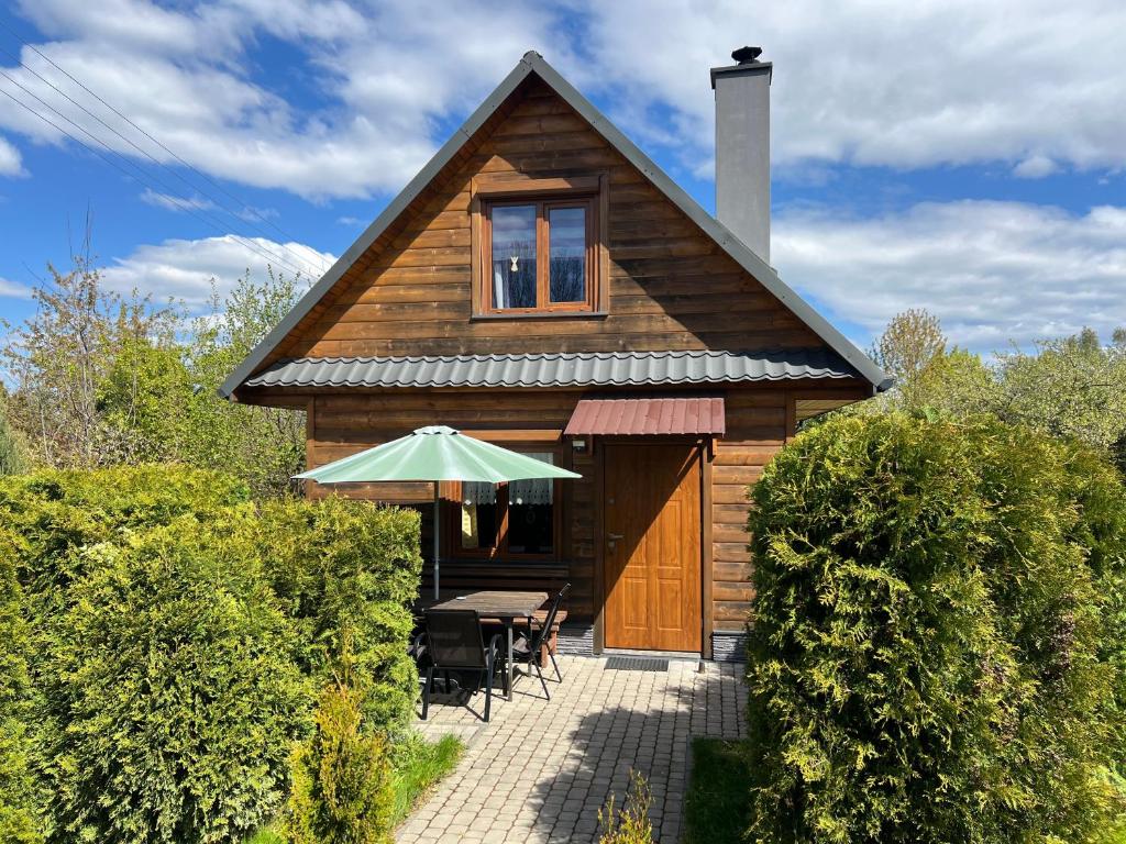 a wooden cabin with a table and an umbrella at Domek Twórczy Kąt in Święta Katarzyna