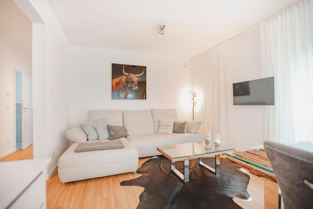 a white living room with a white couch and a table at Ferienbungalow Ochsenkopf in Gefrees