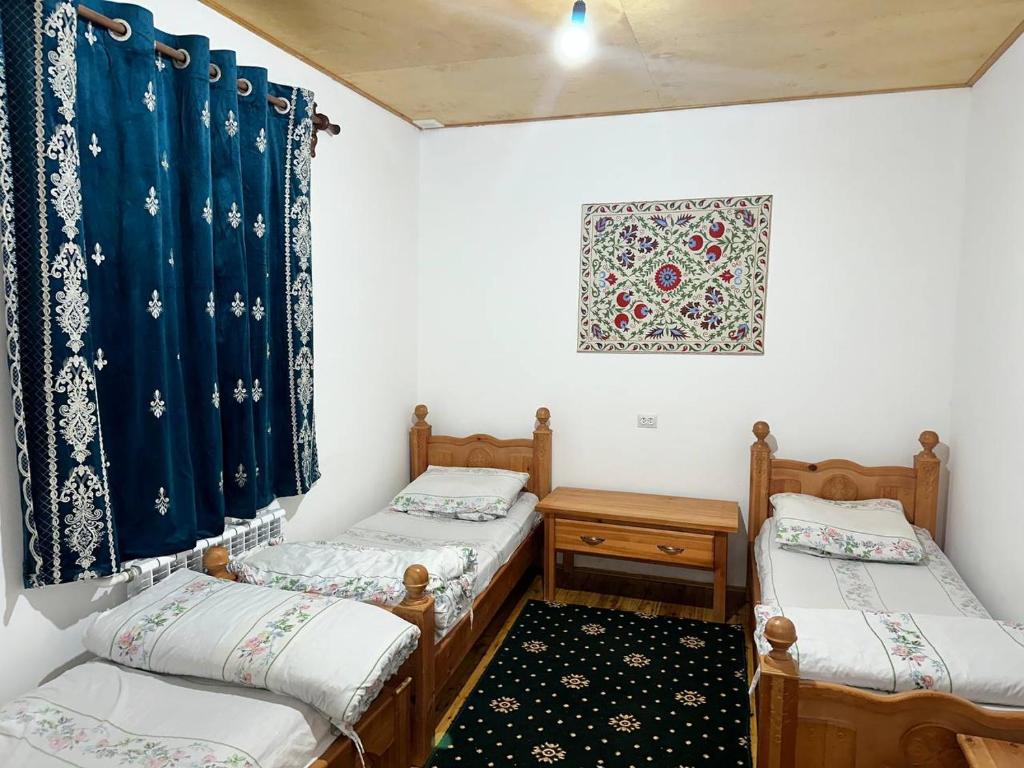 two twin beds in a room with blue curtains at Nurata Eco Guesthouse in Yukary-Ukhum