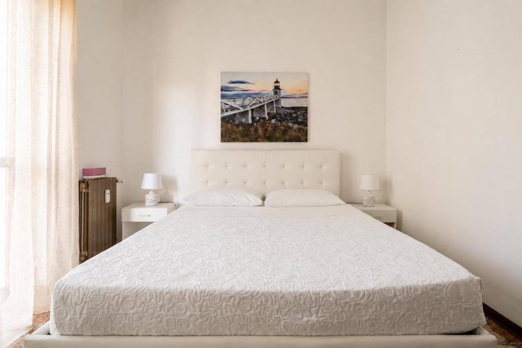 a white bedroom with a large bed and a bridge at oasi corallo in Diano Marina