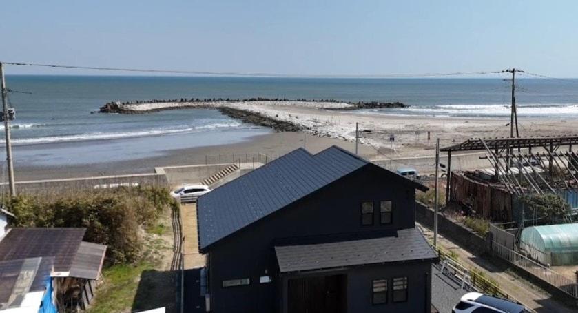 a black house next to a beach with the ocean at 鉾田の家 in Hokota
