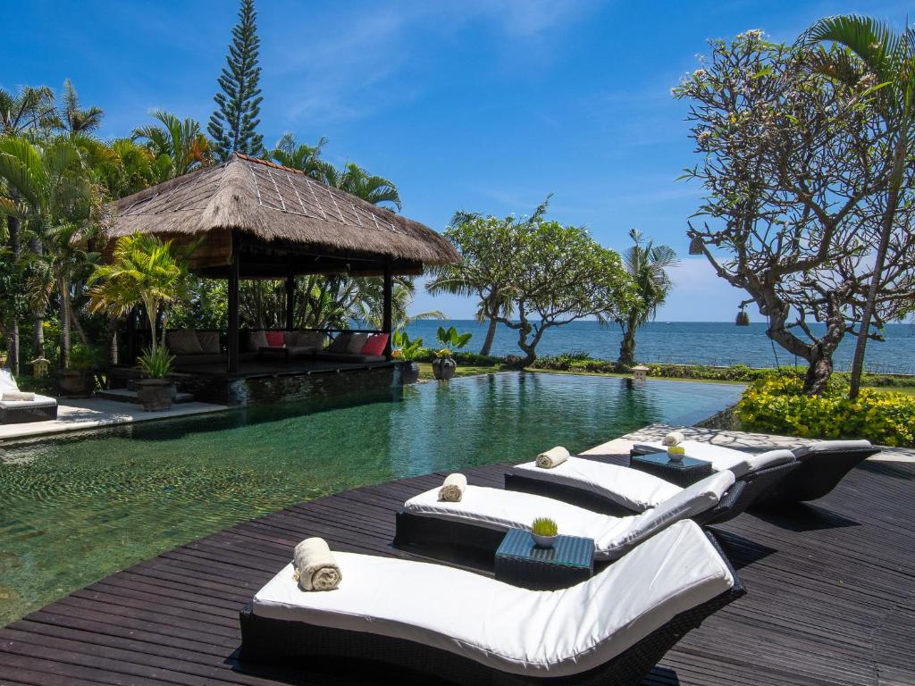 a row of lounge chairs sitting next to a swimming pool at Villa Bossi Bali at Tanguwesia in Bubunan