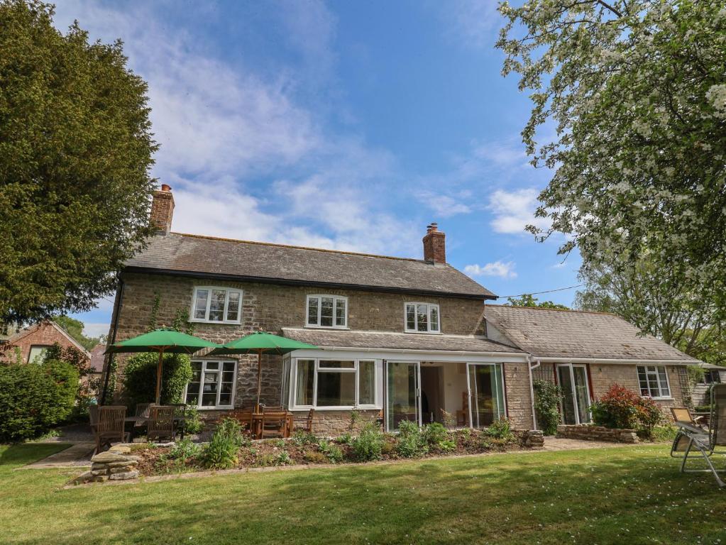 a brick house with green umbrellas in the yard at Harbins Farm in Sherborne