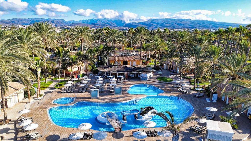 an aerial view of a resort pool with palm trees at Suites & Villas by Dunas in Maspalomas