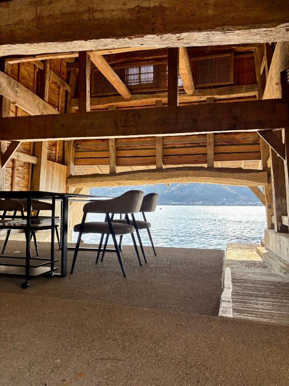 a table and a chair in a building with the water at 伊根の舟屋 樹 Funaya Inn Tatsuki , Ine in Kameshima