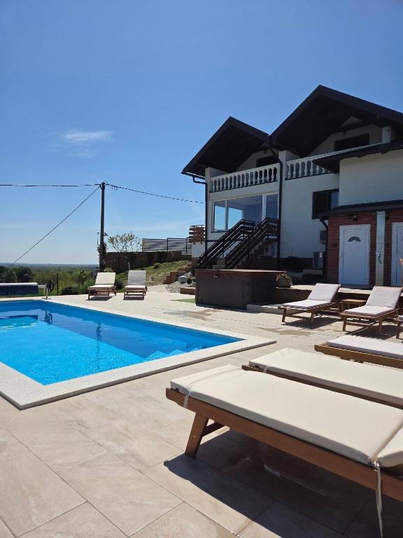 a swimming pool with lounge chairs and a house at Kraljeva Kruna - kuća za odmor in Koprivnica