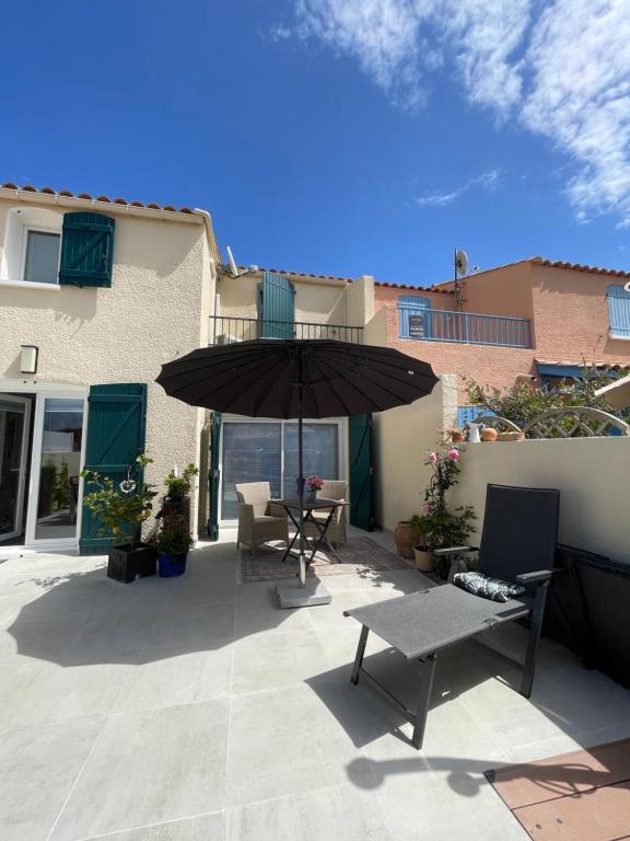 a patio with an umbrella and a table and chairs at Maison Lagune bleue Gruissan in Gruissan