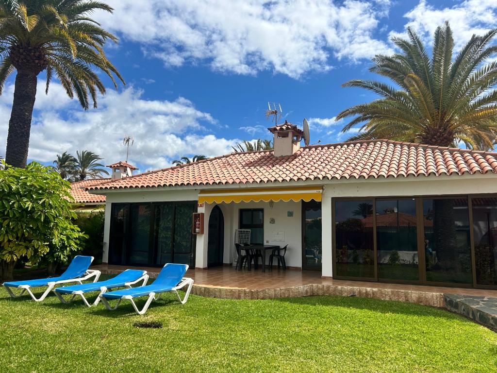 a house with blue chairs and palm trees at Sun Club Bungalows in Playa del Ingles