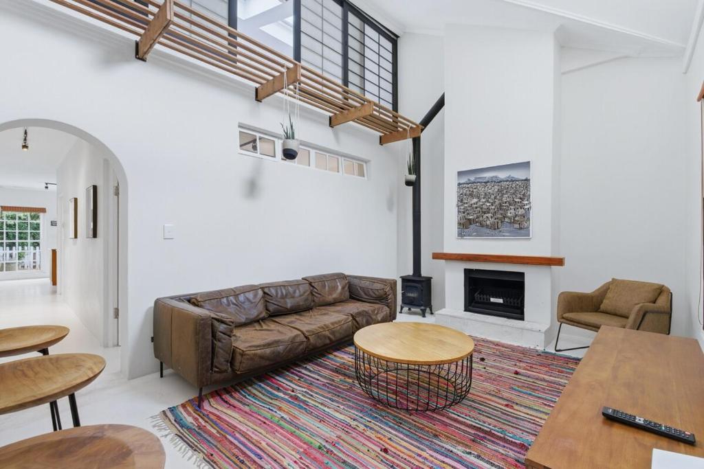 a living room with a couch and a fireplace at Modern Cozy Upper Wynberg Cottage in Cape Town