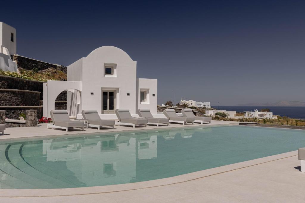 a swimming pool with chairs and a villa at Filomare Oia Suites in Oia