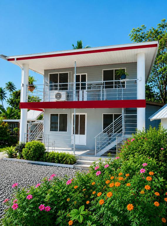 a white house with a balcony and flowers at Nadi Holiday House in Nadi