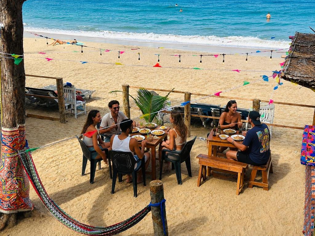 a group of people sitting at a table on the beach at Surf Wave Hotel in Arugam Bay