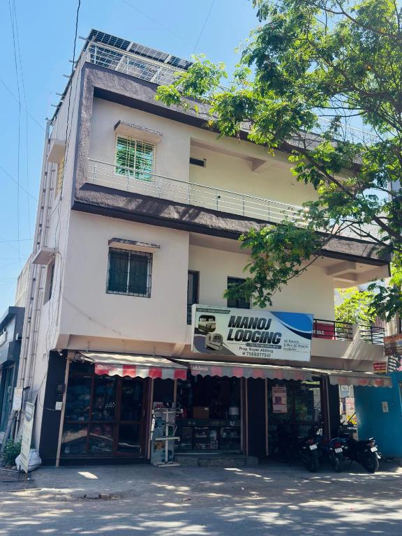 a tall building with a store in front of it at manoj lodge in Sangamner