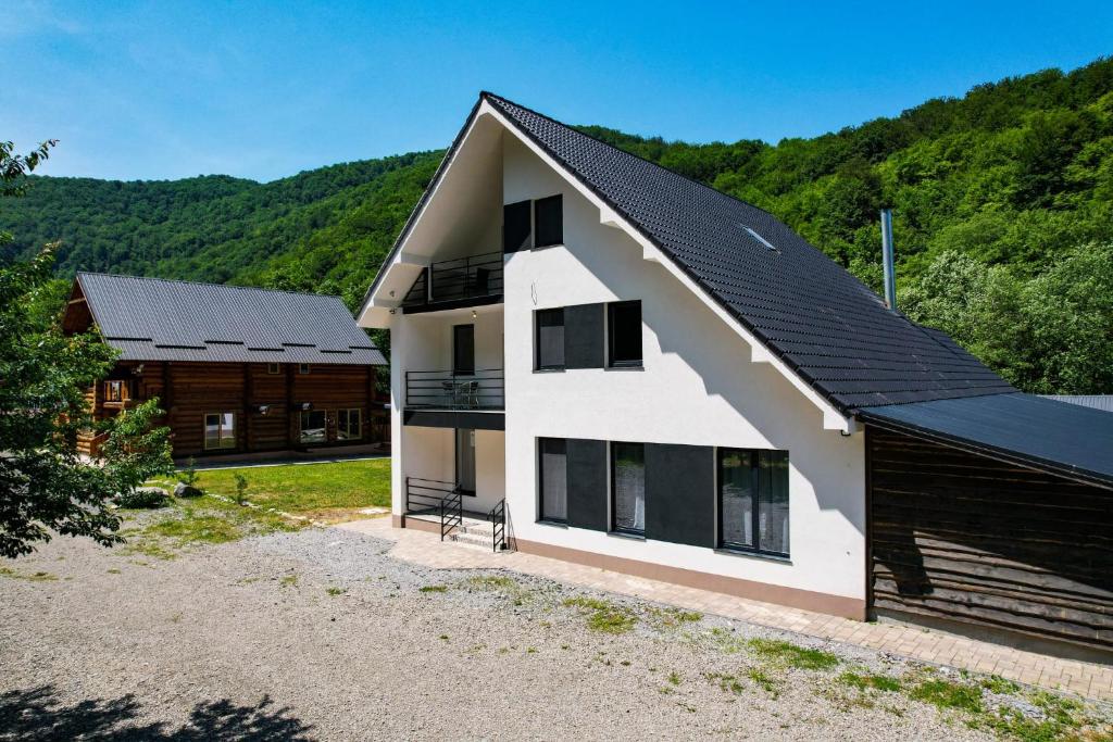 a white house with a black roof at Craiasa Draganului in Poeni