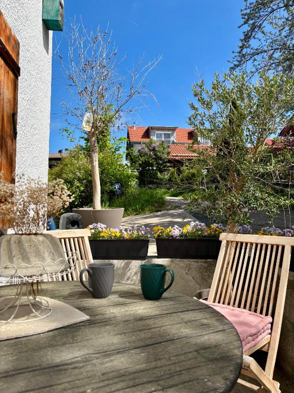 a wooden table and chairs on a patio with flowers at Landhaus am Weissensee in Füssen