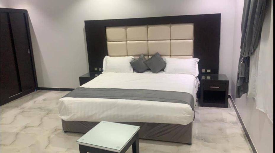a bedroom with a large bed with a black headboard at الشرفة هوم للشقق المخدومة in Najran