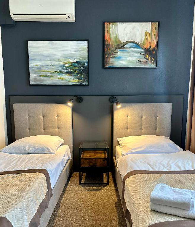 two beds in a room with blue walls at Centrum Konferencyjno-Apartamentowe Mrówka in Warsaw