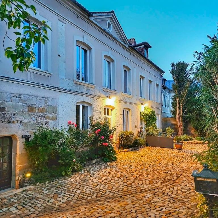 a large white house with a cobblestone driveway at L'Écrin Love Room Spa privatif Orbec in Orbec-en-Auge